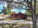 Exterior shot of a quaint red house with a welcoming porch and well-maintained front yard at 111 Water Tank Rd, Haines City, FL 33844