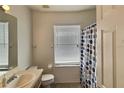 Bright bathroom with a single sink vanity, toilet, and shower/tub combination with polka dot curtain at 114 Langham Dr, Davenport, FL 33897