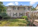 Inviting two-story home with awnings, a red front door, and lush landscaping at 1508 Delaney Ave, Orlando, FL 32806