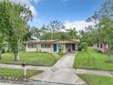 A single-story home with a well-maintained lawn, solar panels, and a walkway that leads to a vibrant blue front door at 23 Judith Ln, Orlando, FL 32811