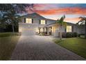 Inviting two-story home with brick-paved driveway and a three-car garage beneath a colorful sunset at 3819 Breckinridge Ln, Clermont, FL 34711