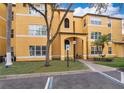 Close-up of a cheerful yellow apartment building featuring an arched entryway and a manicured green space at 4536 Commander Dr # 1537, Orlando, FL 32822