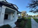 Inviting front porch with substantial columns, a dark front door, and landscaped garden at 7606 Loon Ave, Winter Garden, FL 34787