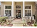 Elegant front porch featuring stone accents, stately columns, and a stylish front door with transom window at 10742 Boca Pointe Dr, Orlando, FL 32836