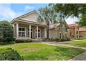 Charming beige house featuring a stone facade, elegant columns, a small balcony, and mature landscaping at 10742 Boca Pointe Dr, Orlando, FL 32836