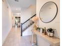 Bright entryway boasts tiled floors, staircase with black iron railing, and decorative table with round mirror at 2377 Reading Trl, Kissimmee, FL 34746