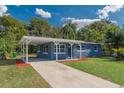 Charming single-story home with blue stone accents, a well-manicured lawn, and a covered carport and long driveway at 705 Liberty St, Eustis, FL 32726