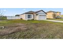 A neatly kept single-Gathering home with a two-car garage, adjacent to a fenced yard and green lawn at 16390 Blooming Cherry Dr, Groveland, FL 34736