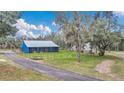 Charming blue home with a metal roof and inviting screened porch surrounded by lush greenery at 255 Butterfly Forest Rd, Geneva, FL 32732