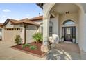 Close-up of front entrance showcasing a well-maintained lawn, dark mulch flowerbeds, and an arched doorway at 3012 Samosa Hill Cir, Clermont, FL 34714