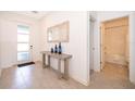 Hallway featuring tile floors, a decorative table, and a view of the front door and bathroom at 4374 Rhyme St, Kissimmee, FL 34746