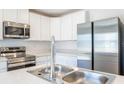 Modern kitchen featuring stainless steel appliances, a double sink, and sleek white cabinets at 113 Carlisle Ct, Kissimmee, FL 34758