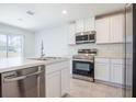 Bright kitchen with stainless steel appliances, white cabinets, and an island with a sink and dishwasher at 113 Carlisle Ct, Kissimmee, FL 34758