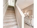 Carpeted staircase leads to the upper level, featuring a neutral color palette and a decorative console table at 1839 Waggoner St, Kissimmee, FL 34744