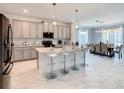 Bright, open kitchen with gray cabinets, marble tile floors, stainless steel appliances, and adjacent dining area at 2908 Protagonist St, Kissimmee, FL 34746
