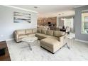 Open-concept living room with a large sectional sofa, marble floors, and seamless access to the kitchen and dining area at 2908 Protagonist St, Kissimmee, FL 34746
