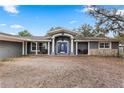 Inviting home exterior with a blue door, gray facade, stone accents, and seating on the front porch at 37224 Apiary Rd, Grand Island, FL 32735