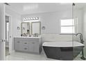 Modern bathroom with a freestanding black tub, gray double vanity, updated lighting, and large window for natural light at 4100 Cannon Ct, Kissimmee, FL 34746
