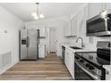 Modern kitchen featuring stainless steel appliances, white cabinetry, and wood-style flooring at 4135 Iveyglen Ave, Orlando, FL 32826