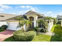 Well-landscaped home featuring a brick driveway, a two-car garage, and a red front door at 53 High Vista Dr, Davenport, FL 33837