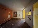 Spacious living room showcasing hardwood floors, peeling paint, and natural light from a front window at 115 S Lake Pleasant Rd, Apopka, FL 32703