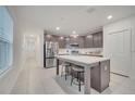 Modern kitchen featuring a center island with seating, stainless steel appliances, and tile flooring at 4057 Sagefield Dr, Harmony, FL 34773