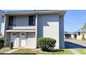 View of the exterior of a light gray condo complex showcasing the front doors and surrounding greenery at 4448 Pinebark Ave # 56-1, Orlando, FL 32811
