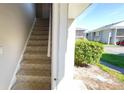 Stairway to the main level showing the beige carpet runner, light gray walls and a view of the outdoors at 4448 Pinebark Ave # 56-1, Orlando, FL 32811