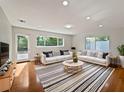 Bright living room with hardwood floors, white sofas, striped rug, and large windows offering a view of outdoor greenery at 662 Lake Dr, Altamonte Springs, FL 32701
