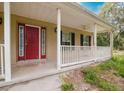 The front porch features a concrete floor, a white fence, a ceiling fan, and a red front door at 6801 County Rd 665, Bushnell, FL 33513