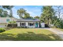 Well-manicured front lawn and landscaping with an inviting white exterior and a striking blue front door at 1410 Osceola Ct, Orlando, FL 32806