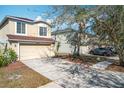 Two-story home with a beige exterior, a brown roof, green plants and a cement driveway at 15323 Torpoint Rd, Winter Garden, FL 34787