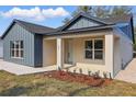 This home has a inviting covered porch, modern siding and manicured garden bed with vibrant foliage at 355 Anderson Dr, Groveland, FL 34736