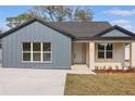 Inviting single-Gathering home with a well-manicured lawn, modern gray siding, and a bright white front door at 355 Anderson Dr, Groveland, FL 34736