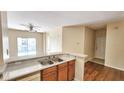 Kitchen featuring wood cabinets, stainless steel sink, and stone countertops open to the living and dining area at 8103 Lillies Way # 202, Orlando, FL 32825