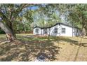 Quaint single-story home with white siding and black trim framed by mature trees on a spacious lot at 850 Rosalia Dr, Sanford, FL 32771