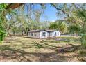 Inviting single-story home with white siding and black trim nestled among mature trees on a grassy lawn at 850 Rosalia Dr, Sanford, FL 32771