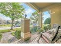 Cozy porch with brick flooring, decorative columns, comfortable seating, and a view of the neighborhood at 9130 Sabal Pine Way, Orlando, FL 32832