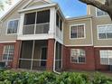 Two-story condo with neutral siding, red brick accents, and a screened-in porch for relaxing outdoors at 13028 Plantation Park Cir # 1218, Orlando, FL 32821