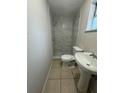 Bathroom featuring a sink, toilet, and marble-tiled walk-in shower at 220 Palm Ave, Auburndale, FL 33823