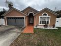 Inviting home with a cozy, red brick walkway, gray double garage door, and verdant landscaping in front yard at 7132 Laurel Hill Dr, Orlando, FL 32818