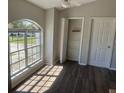 Bright living room featuring a large arched window, plenty of natural light, and dark wood flooring at 7277 Pebble Pass Loop Loop, Lakeland, FL 33810