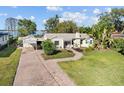 Charming single-story home with a brick driveway, lush greenery, and a glimpse of the lake at 85 Interlaken Rd, Orlando, FL 32804