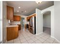 Well-lit kitchen with stainless steel appliances, wood cabinetry, and tile flooring leading to the living area at 944 Glen Abbey Cir, Winter Springs, FL 32708