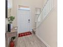 Bright entryway with wood-look flooring, a staircase, and a welcoming red-and-black checkered rug at 1100 Downswing Pl, Davenport, FL 33896