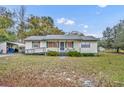 A charming single-story home with a ramp and a covered carport sits on a lot with scattered leaves at 1350 N Hart Rd, Geneva, FL 32732