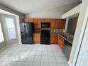 Well-lit kitchen with black appliances, brown cabinets, and a tiled floor at 1103 Jade East Ln # 1103, Kissimmee, FL 34744