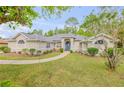 Charming single-story home with lush landscaping, a curved walkway, and a bright blue front door at 27 Foxhunter Flt, Ormond Beach, FL 32174