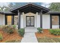 Stunning entryway with double doors, a covered porch, and a symmetrical design with manicured shrubbery at 305 Haverlake Cir, Apopka, FL 32712