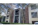 Multi-story condominium exterior featuring brick and siding with balconies, stairs, and mature trees at 5016 Park Central Dr # 2231, Orlando, FL 32839